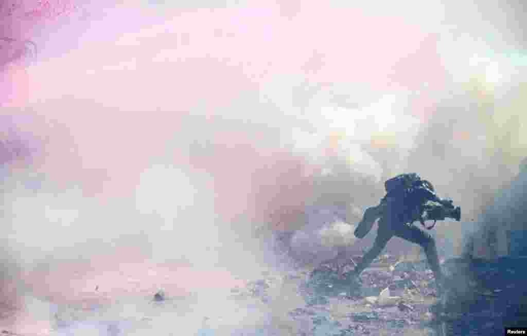 A journalist runs through tear gas lobbed by riot police officers to disperse the convoy of Kenya's opposition leader Raila Odinga of the Azimio La Umoja (Declaration of Unity) One Kenya Alliance, as they participate in a protest over cost of living and President William Ruto's government in Nairobi, Kenya.