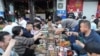 中国山东淄博五一节期间民众在烧烤摊旁品尝烧烤。(2023年5月2日)