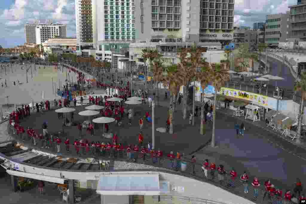 Israeli women&#39;s rights activists form a human chain along the beach to mark International Women&#39;s Day and protest against plans by Prime Minister Benjamin Netanyahu&#39;s new government to overhaul the judicial system, in Tel Aviv.