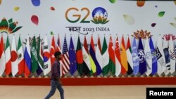 2023年9月8日，新德里G20峰会前，一名男子在会员国国旗前走过。