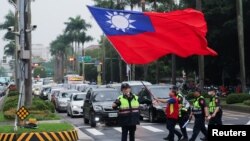 台湾警察护送一名举着台湾旗帜的男子走过台北街头。（2024年5月24日）