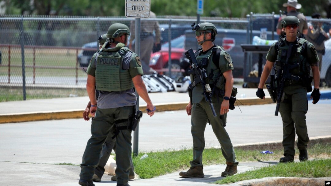 FILE — Law enforcement personnel stand outside Robb Elementary School following a shooting, May 24, 2022, in Uvalde, Texas.