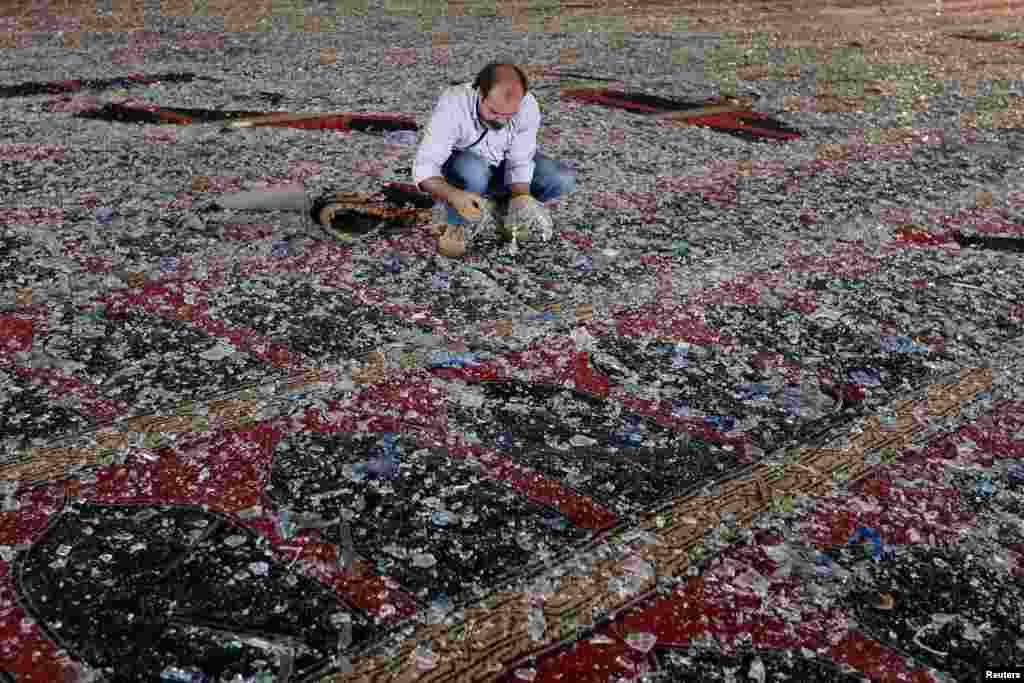 A man removes broken glass scattered on the carpet of a mosque damaged in Tuesday's blast in Beirut, Lebanon.