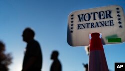 Los votantes pasan frente a un letrero afuera de un sitio de votación en Warwick, Rhode Island, el 7 de noviembre de 2022, después de emitir sus votos el último día de votación anticipada antes de las elecciones de mitad de período en EEUU.