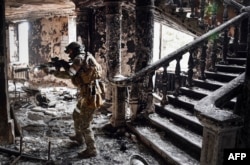 A Russian soldier patrols at the Mariupol drama theater that was bombed last March 16, in Mariupol, as Russian troops intensify a campaign to take the strategic port city, April 12, 2022. (Photo by Alexander NEMENOV / AFP)