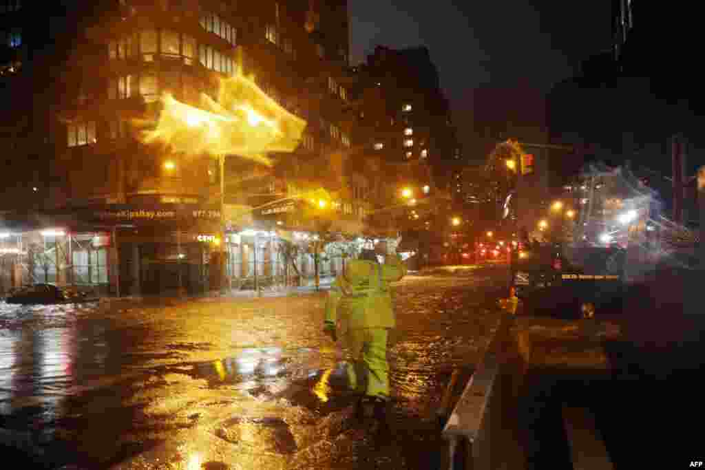 2012年10月29日，爱迪生联合电力公司的一名工人冒雨走过纽约市33街和第一大道街角，前方是曼哈顿的朗格尼医学中心(Langone Medical Center)。(Michael Heiman/Getty Images/AFP)
