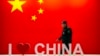 资料照：一名保安人员在北京举行的信息通信展览会上走过“我爱中国”的标语。（2019年10月31日）