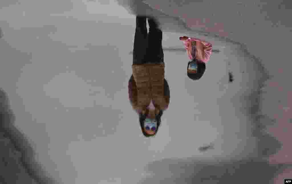 A mother and child wearing face masks are reflected in a puddle while walking in Melbourne's Docklands district in Australia as the city battles an outbreak of the COVID-19 coronavirus.