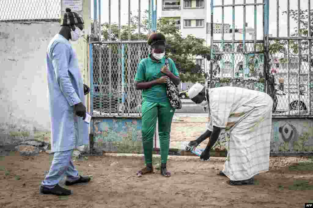 A High School student at the Lycee Blaise Diagne gets her feet disinfected as she arrives for her first day back at school in Dakar, Senegal.