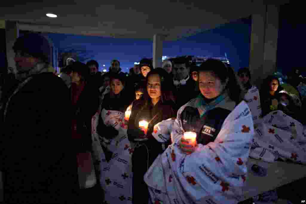 2012年12月16日，在奥巴马总统在纽敦高中举行的一次跨教派烛光守夜仪式上讲话之际，居民们在校外举着蜡烛纪念桑迪.胡克小学枪击案遇难者。