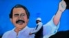 Un hombre, con una máscara facial para protegerse del nuevo coronavirus, camina junto a un mural que representa al presidente nicaragüense Daniel Ortega, en Managua, el 30 de marzo de 2020.
