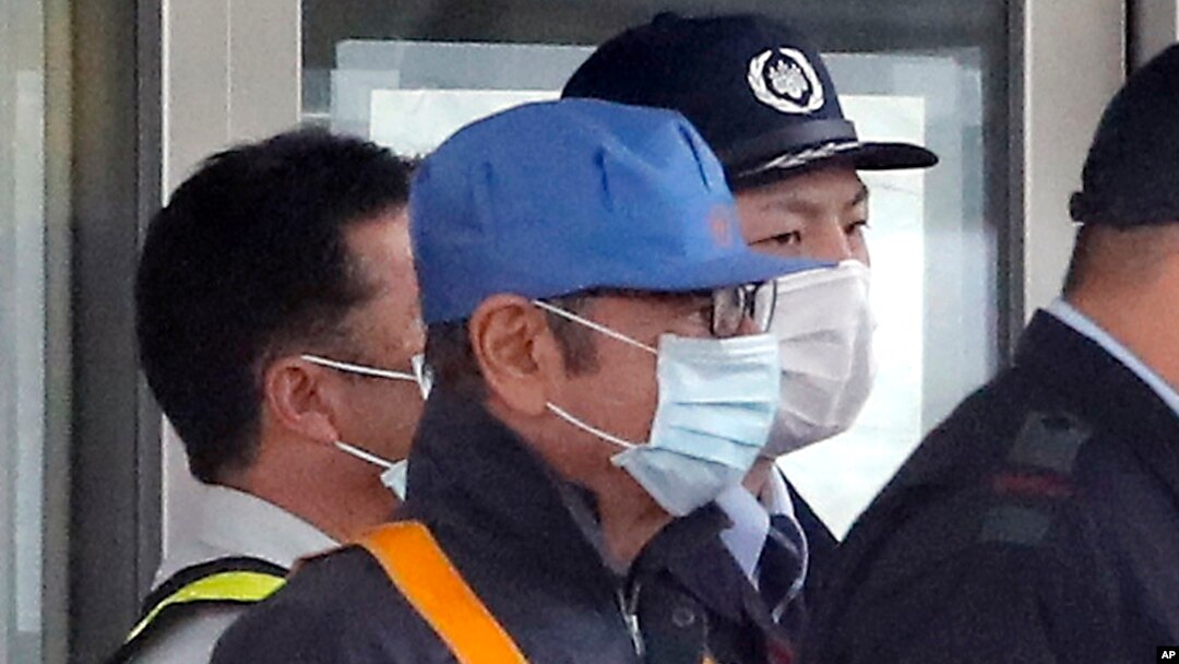 Un hombre cubierto con una máscara facial, que se cree que es el expresidente de Nissan Carlos Ghosn (centro, con gorra azul), sale del Centro de Detención de Tokio, en Tokio, el 6 de marzo de 2019 tras depositar una fianza.
