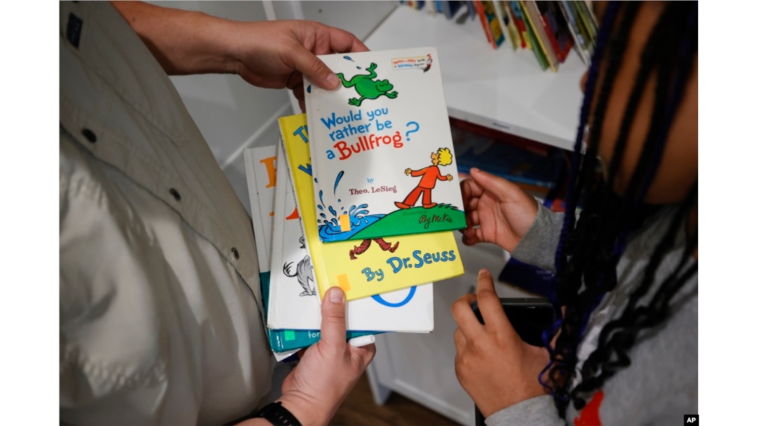 Tim McNeeley, left, helps students pick books to read during an after-school literacy program in Atlanta on Thursday, April 6, 2023. (AP Photo/Alex Slitz)