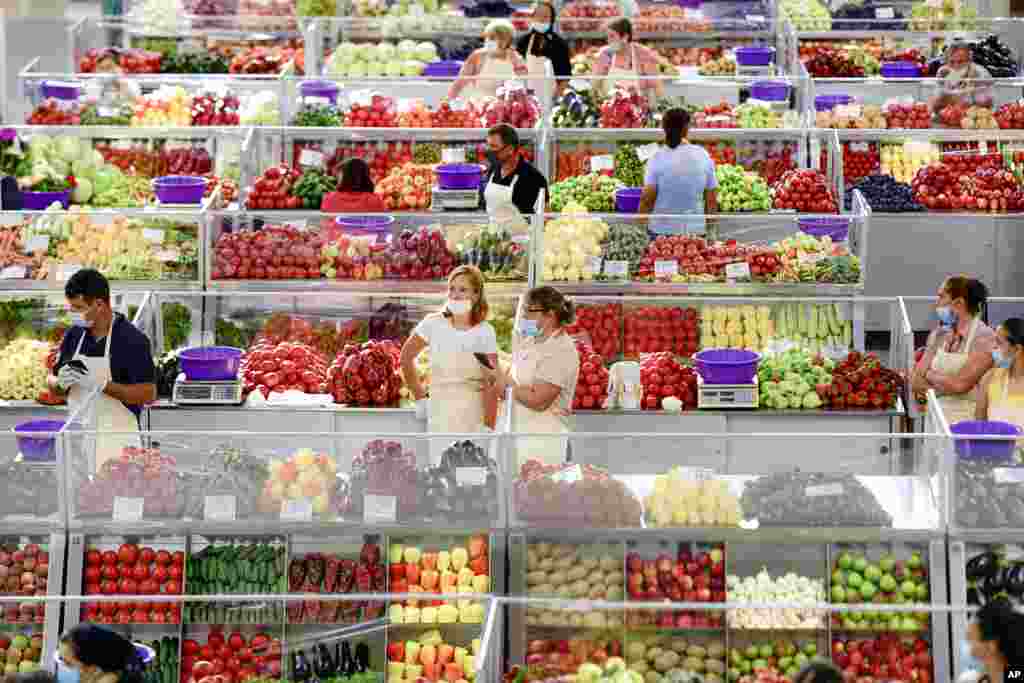 Fruit and vegetable vendors, wearing masks against the spread of the COVID-19 infections, wait for customers at a market in Bucharest, Romania.