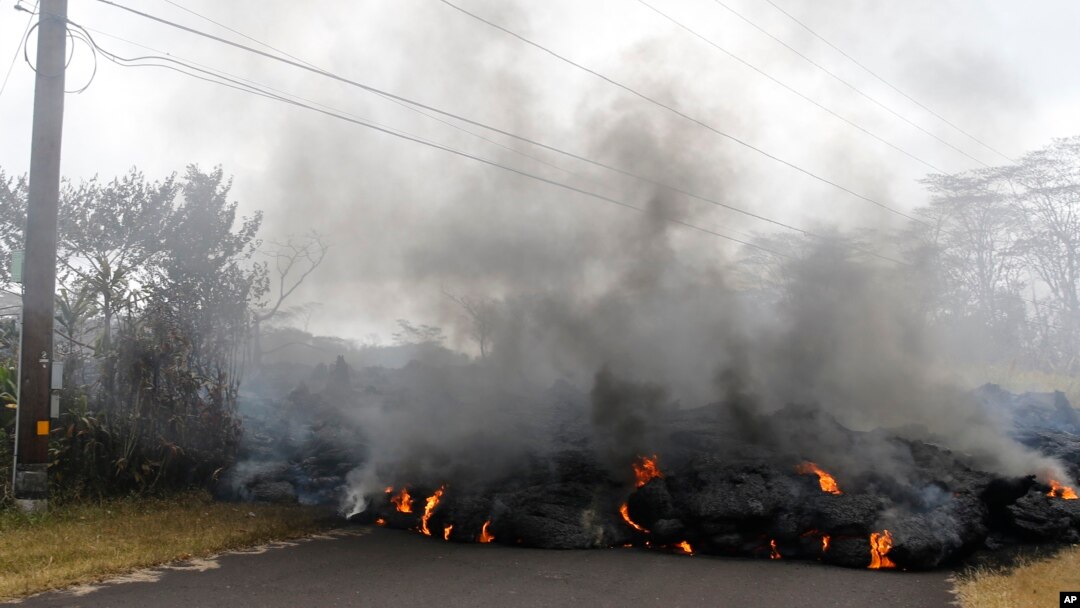 Lava crosses the road near Pohoiki Road, May 18, 2018, near Pahoa, Hawaii. Several open fissure vents are still producing lava splatter and flow in evacuated areas. Gas is also pouring from the vents, cloaking homes and trees in smoke. 